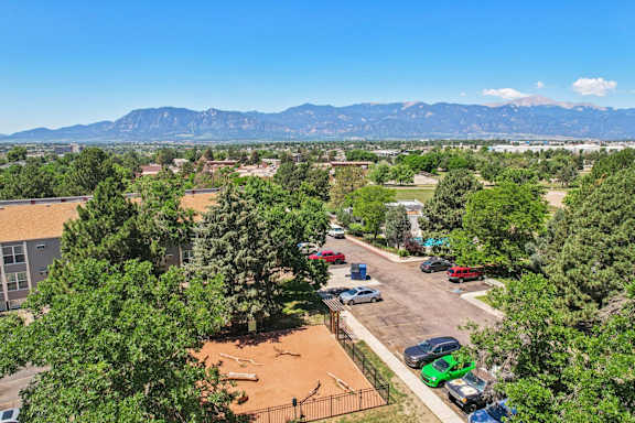 A parking lot with cars and a mountain range in the background at The Montecito, Colorado Springs