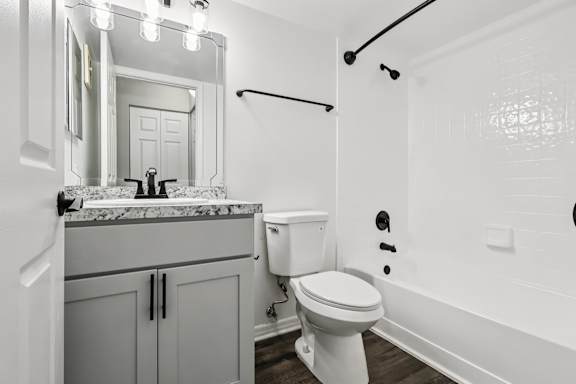 A white toilet in a bathroom with a marble countertop and a mirror above it. at Lakeside Glen Apartments, Melbourne, 32904