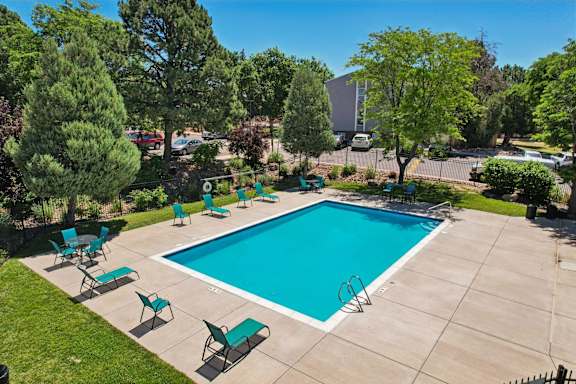 A swimming pool surrounded by green trees and lawn chairs at The Montecito, Colorado Springs