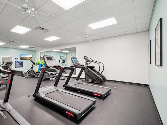 Three treadmills are lined up in a row in a gym.