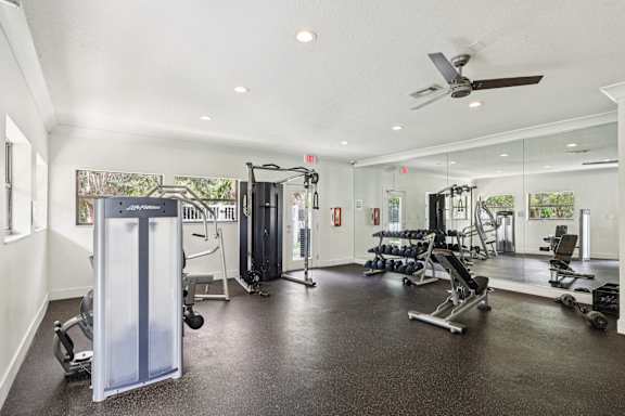 A spacious gym with a variety of equipment including a squat rack, bench, and weights. at Lakeside Glen Apartments, Melbourne, FL