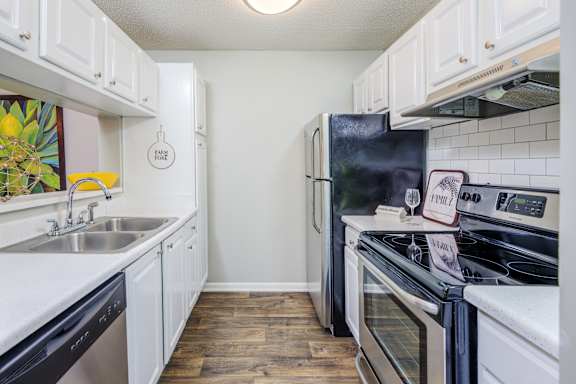 A kitchen with white cabinets and black appliances at The Pointe at Irving Park, Greensboro, NC, 27408