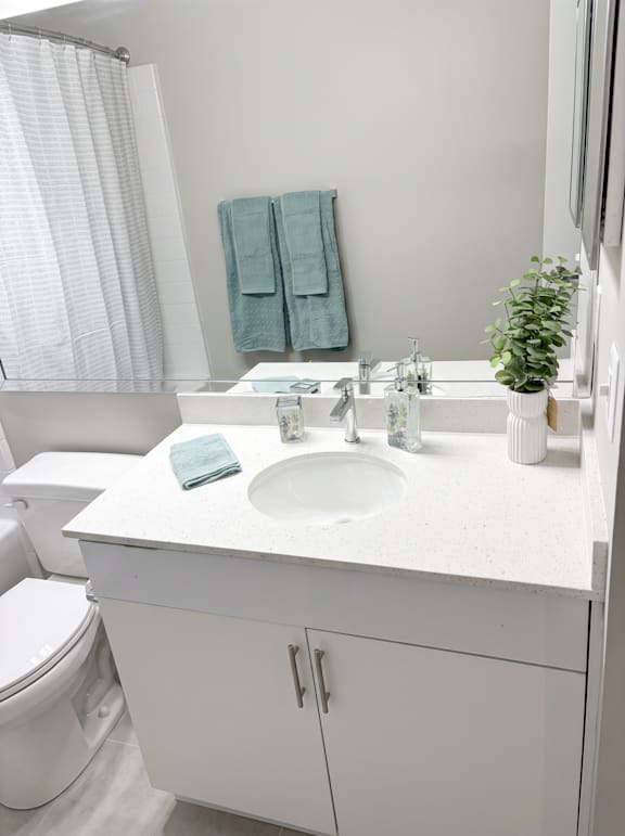 A white bathroom with a toilet, sink, and towels.
