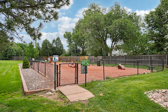 A tennis court surrounded by a fence and trees at Broadmoor Springs, Colorado Springs