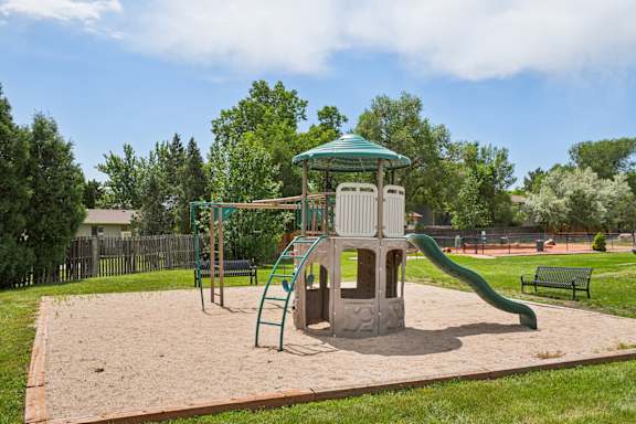 A playground with a green slide and a wooden structure at Broadmoor Springs, Colorado Springs