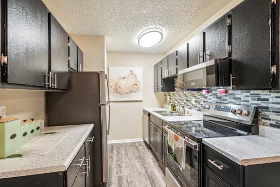 A kitchen with black cabinets and a white countertop at The Montecito, Colorado Springs