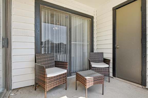 Two chairs and a table are on a porch at The Glen at Highpoint, Dallas