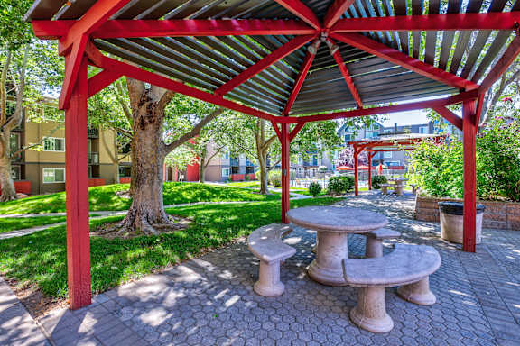 A red and white pavilion with a picnic table underneath it.