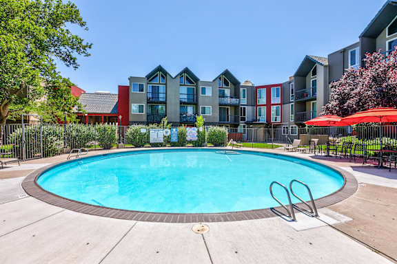 A swimming pool in front of a multi-story apartment building.