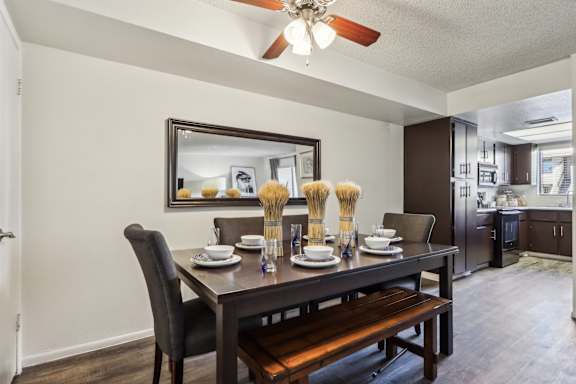 A dining room with a table set for two and a bench.