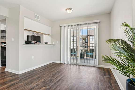 A living room with a wooden floor and a sliding glass door at The Glen at Highpoint, Dallas