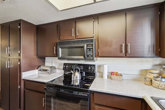 A kitchen with brown cabinets and a black stove top oven.