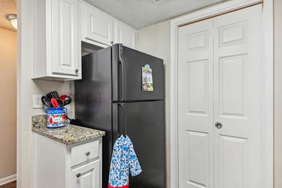 A black refrigerator with a blue and white shirt hanging on it at The Glen at Highpoint, Dallas
