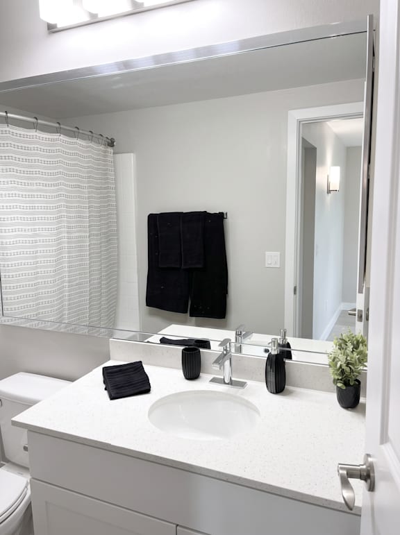 A white bathroom sink with a black towel and a black soap.