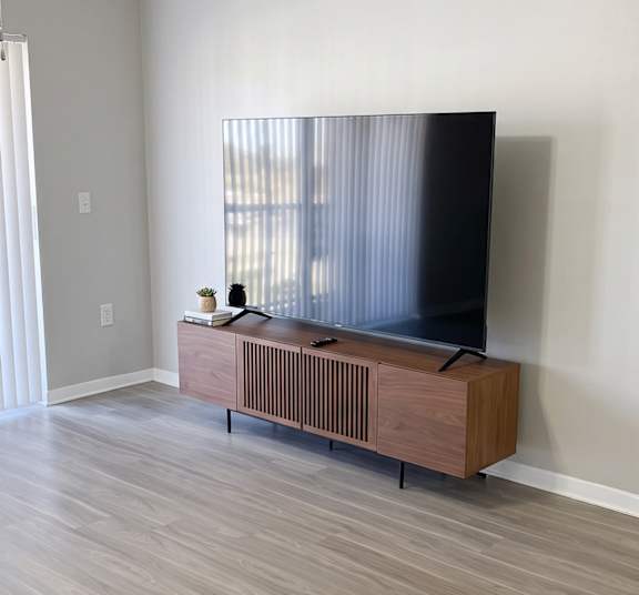 A black flat screen TV on a wooden stand in a room.