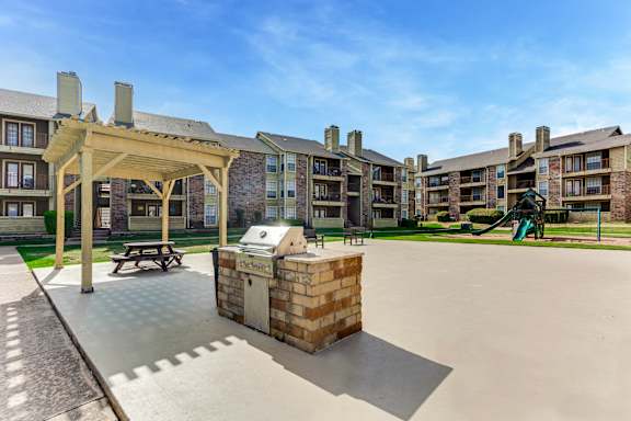 A sunny day at a residential complex with a playground and a picnic table at The Glen Apartments, Lewisville, Texas