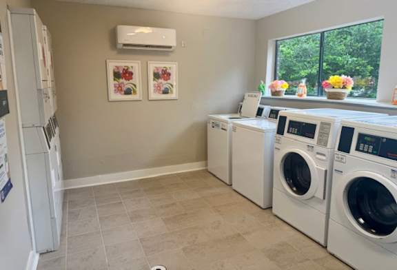 A laundry room with a washer and dryer, a refrigerator, and a window.
