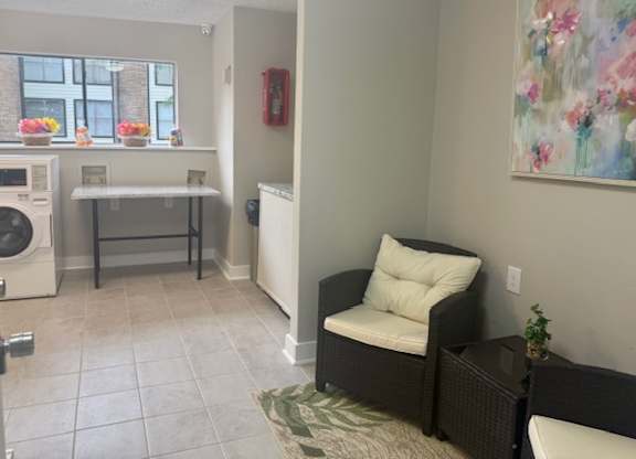 A room with a washing machine and a chair.