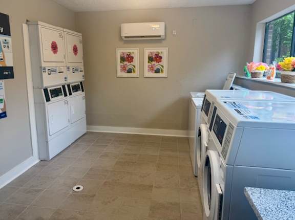 A laundry room with a washer and dryer, a refrigerator, and a wall with two framed pictures.
