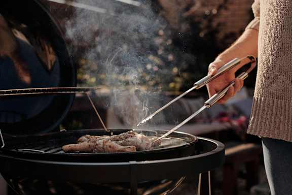 a person is grilling food on a grill at The Pointe at Irving Park, Greensboro, North Carolina