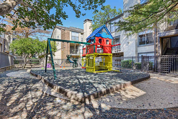 A playground with a red and yellow slide and a blue and yellow playhouse.