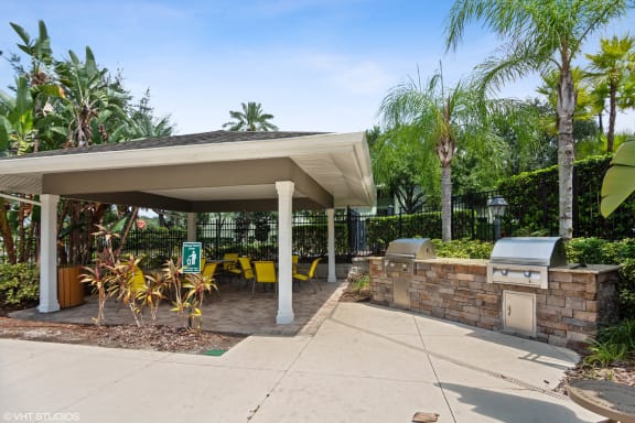Outdoor grilling area with covered pavilion seating at The Arbor Walk Apartments, Florida