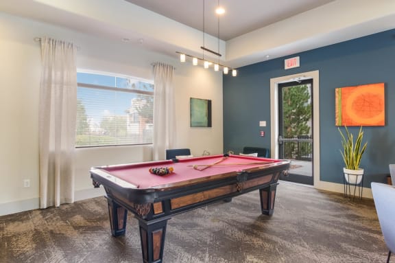 A pool table in a room with a window and a painting on the wall. at Broadstone Towne Center, Albuquerque, New Mexico