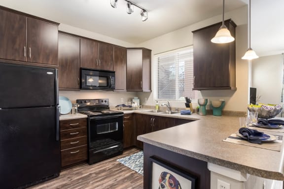 A kitchen with dark wood cabinets and a black refrigerator. at Broadstone Towne Center, Albuquerque, New Mexico