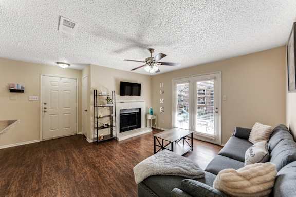 A living room with a grey couch and a fireplace at The Glen Apartments, Lewisville, Texas