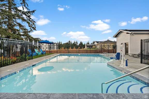 A large outdoor swimming pool with a blue sky and clouds in the background.