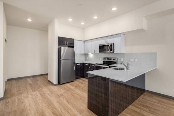 A kitchen with a refrigerator, microwave, and sink.