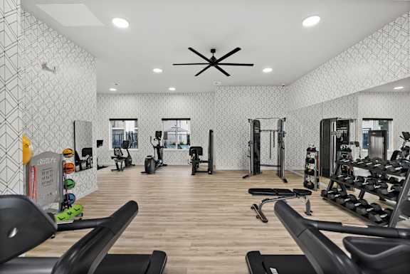 A gym with a variety of equipment including treadmills, weights, and exercise machines.