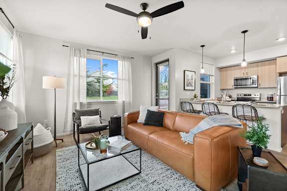 A living room with a brown leather couch and a glass coffee table.