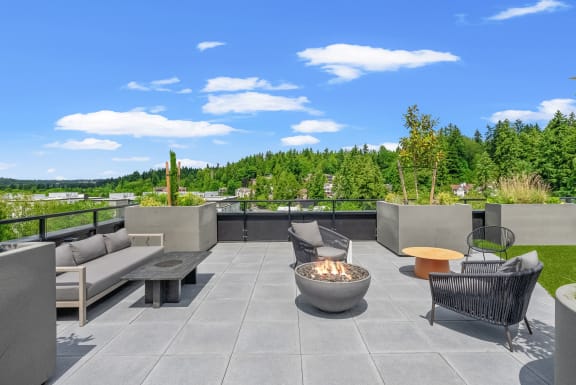 a rooftop patio with couches and tables and a fire pit at Hue Apartments, Redmond, 98052