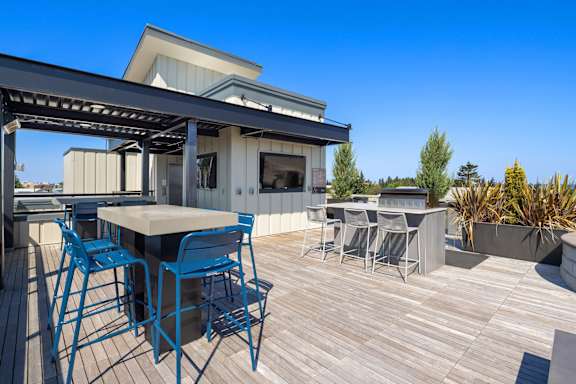 A modern outdoor dining area with blue chairs and a wooden table.