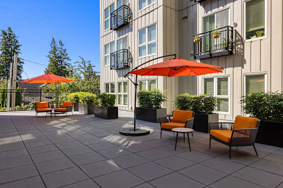 A patio with orange chairs and umbrellas.