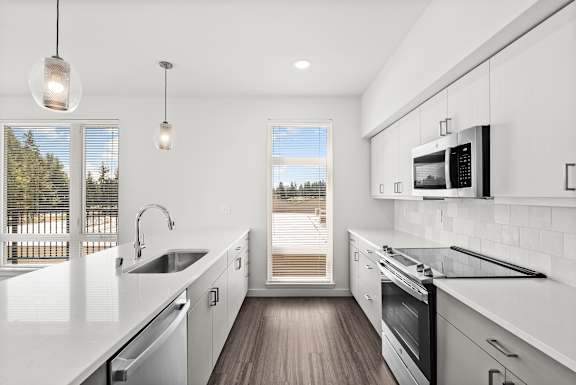 A modern kitchen with white cabinets and appliances.