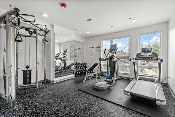 A gym with a variety of equipment including treadmills, weights, and exercise machines.