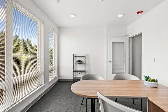 A conference room with a table, chairs, and a plant on the table.