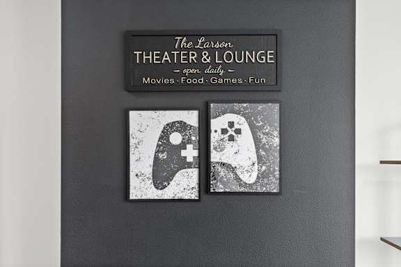 A wall with a sign that says "The Larson THEATER & LOUNGE" and two pictures of a video game controller and a ghost.