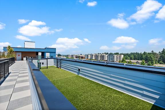 A modern building with a blue and white exterior is surrounded by a grassy area and a clear blue sky.