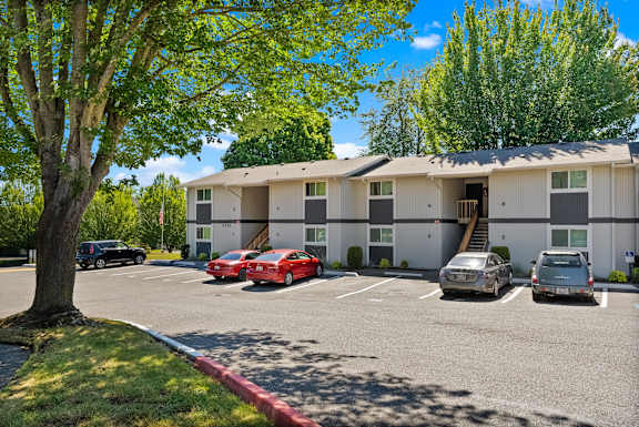 A parking lot in front of a building with cars parked.