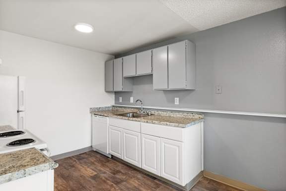 A kitchen with white cabinets and a granite countertop.
