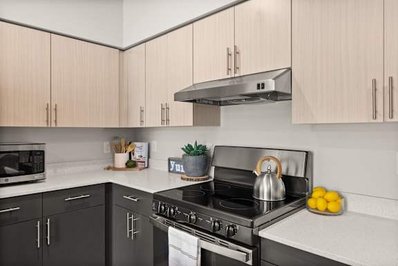 A modern kitchen with a black stove top oven and wooden cabinets.