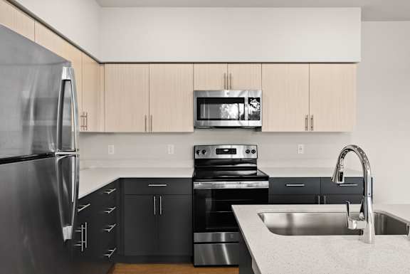 A modern kitchen with black appliances and wooden cabinets.