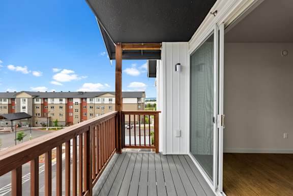 A balcony with a glass door leading to a room.