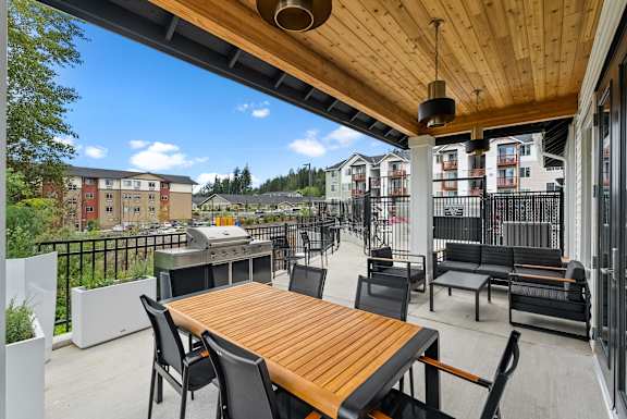 A wooden table is surrounded by chairs on a patio.