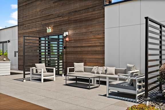 A patio with white furniture and a wooden wall.