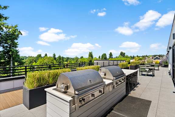 A rooftop patio with a grill and seating area.
