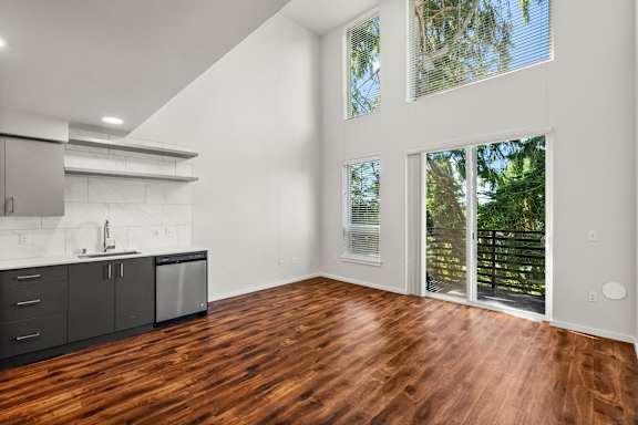A kitchen with dark wood floors and white walls.